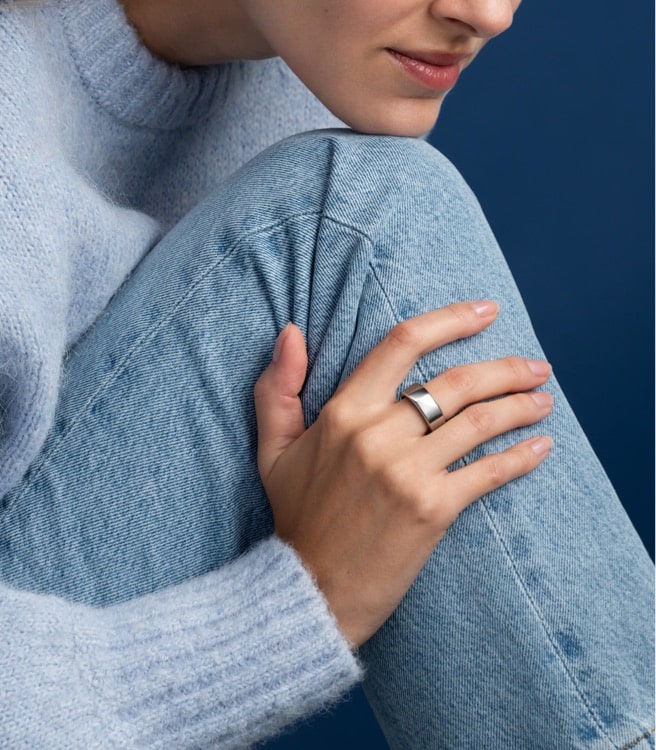 A woman with her chin on her knee wearing the Oura Ring