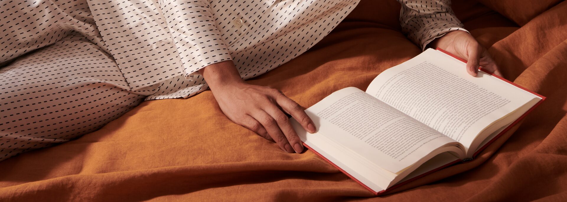 A woman in bed reading a book.