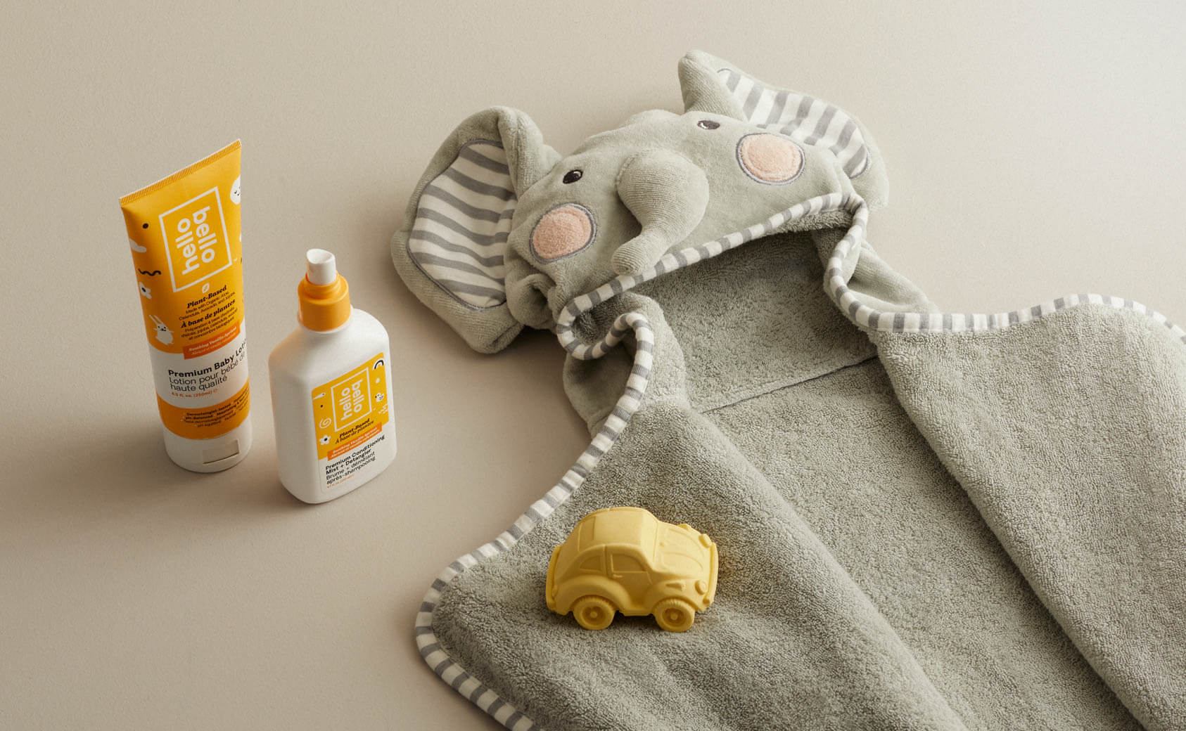 A hooded baby towel laid on a table beside hello bello bath product.