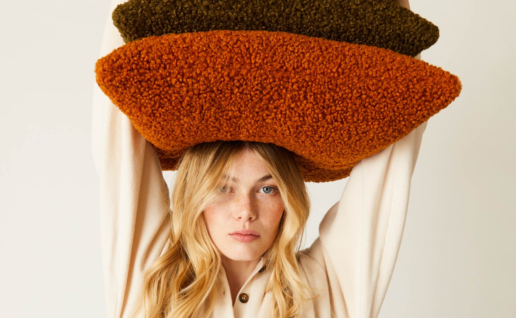 Model holding OUI sherpa throw pillows.