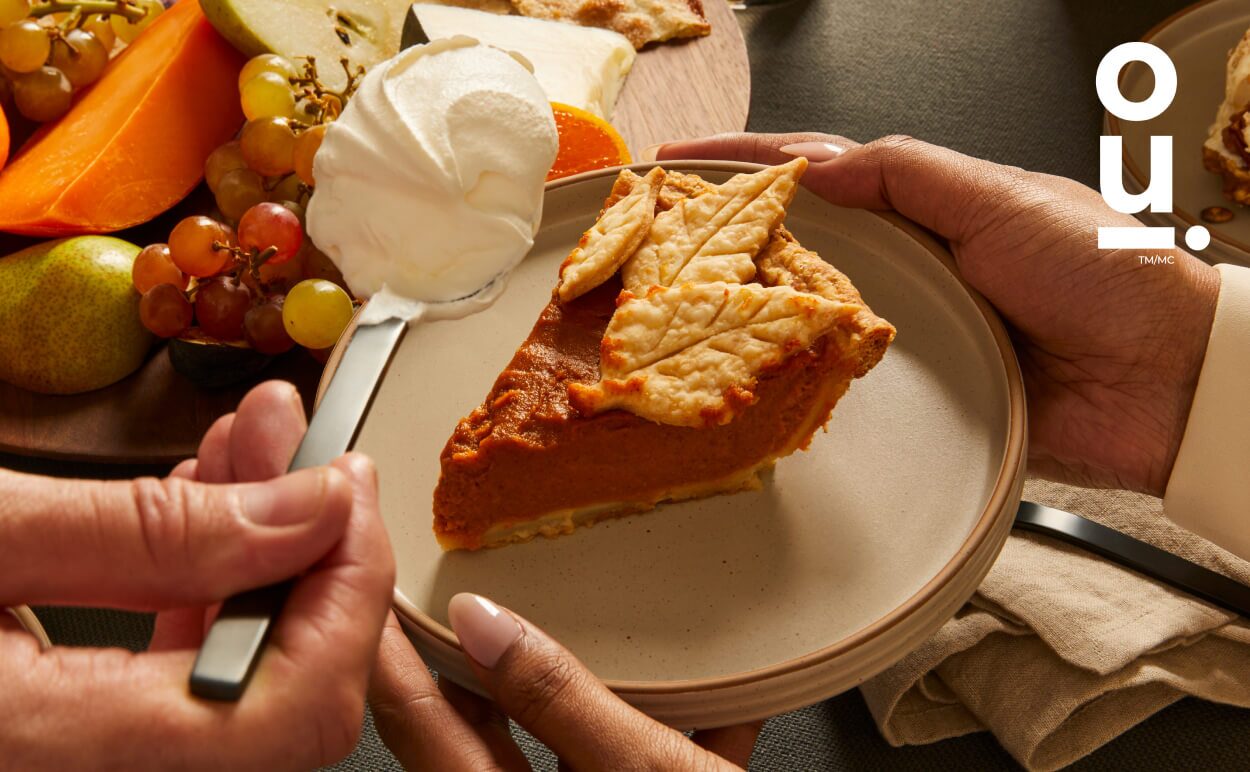 Woman holding a plate with a slice of pumpkin pie on top.
