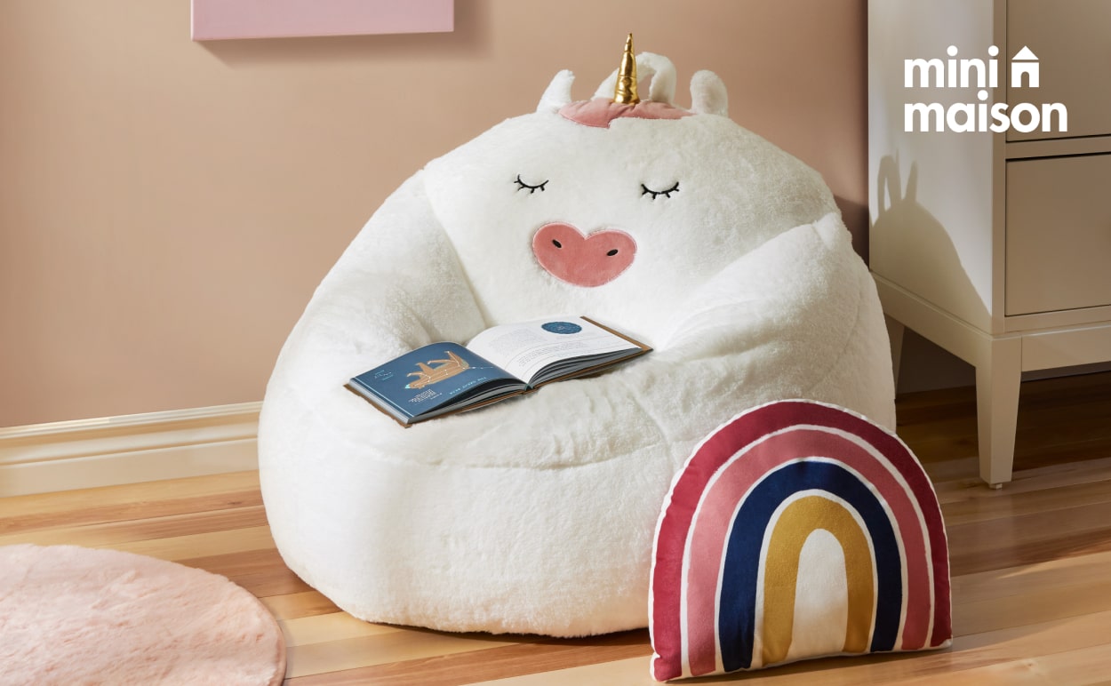 A unicorn themed bean bag chair and rainbow shaped throw pillow