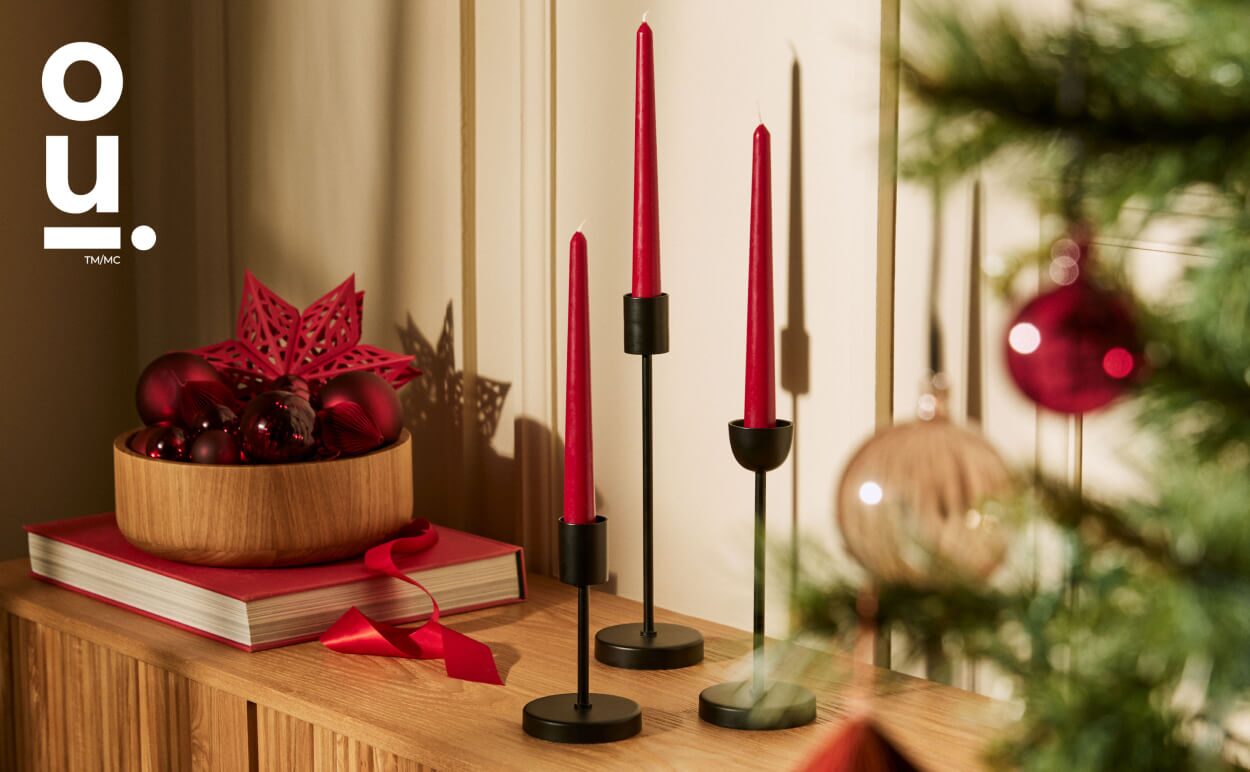 Wooden tabletop featuring OUI black candle holders with red candlesticks.