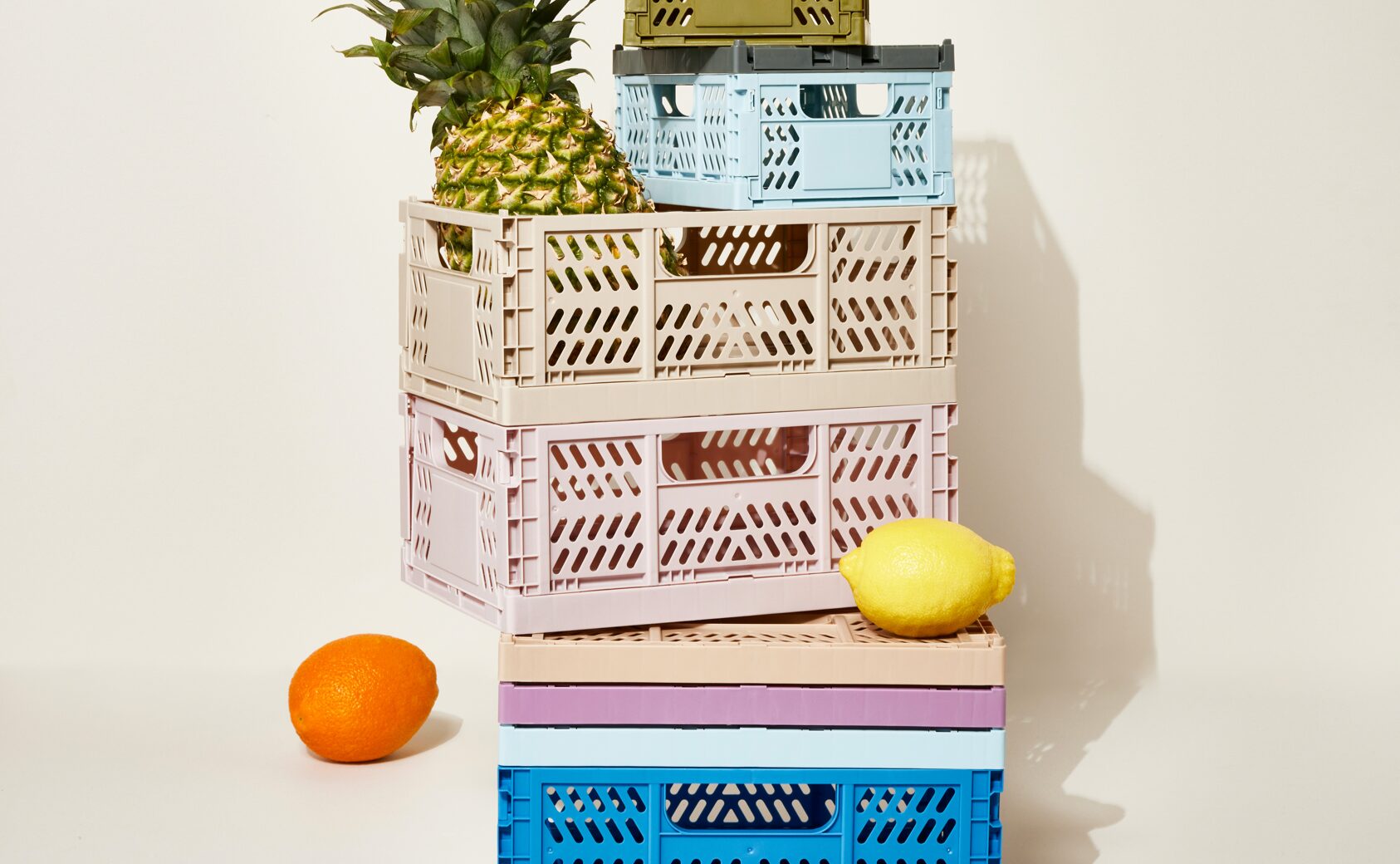 Colourful Oui collapsible stacking crates with some fruit placed inside.