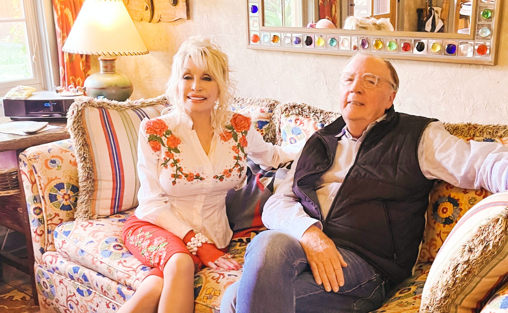 Dolly Parton and James Patterson sitting on a couch together.