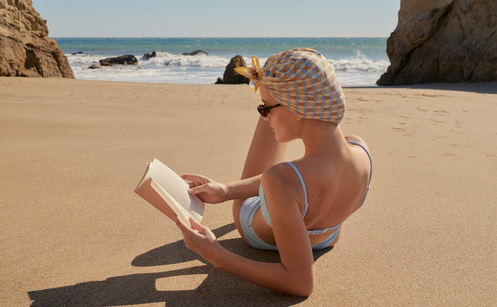 8 Summer-Themed Books as Good as a Vacation: a woman reading a book on the beach
