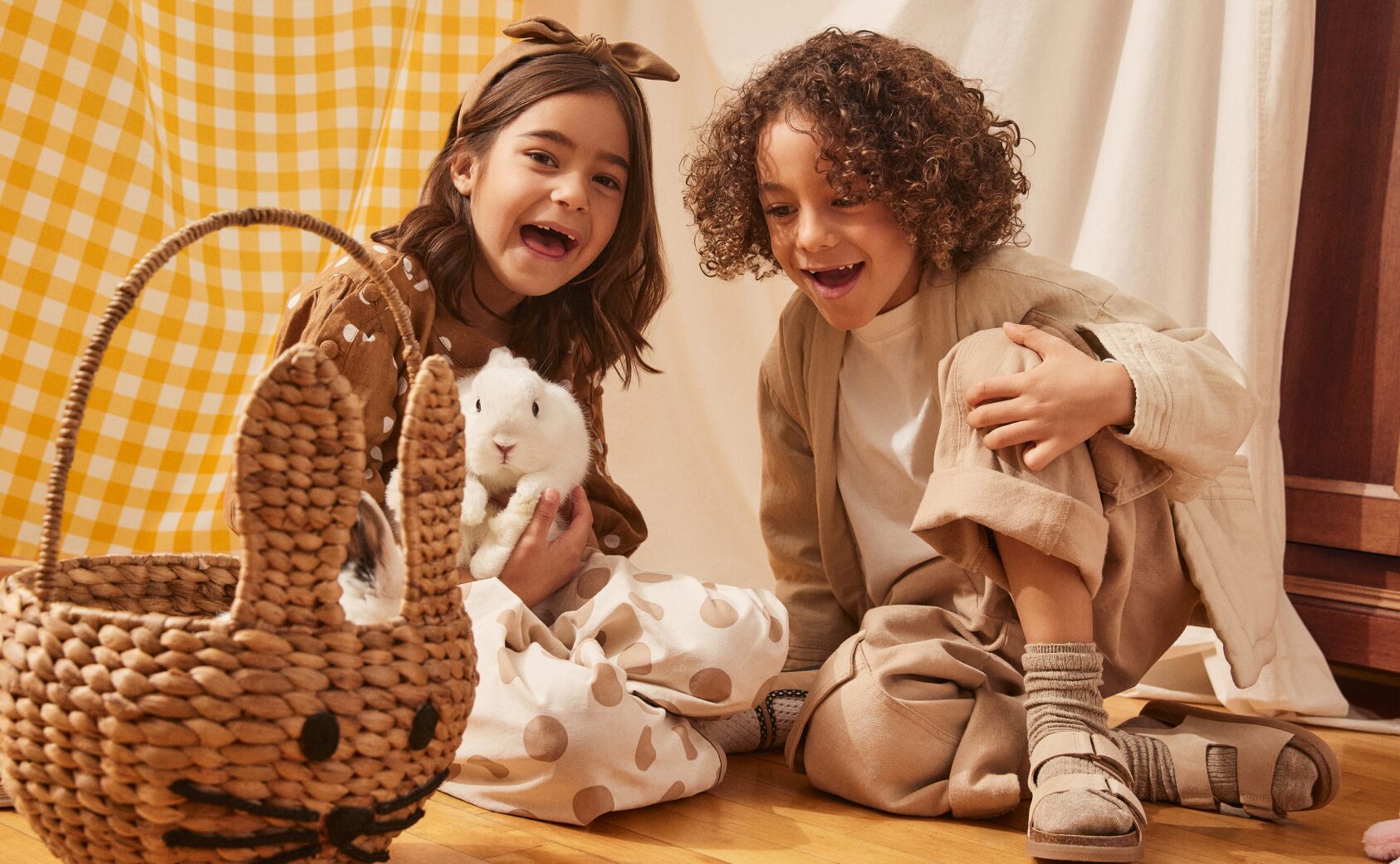 Two kids holding a bunny with the Wonder Co. wicker Easter bunny basket.