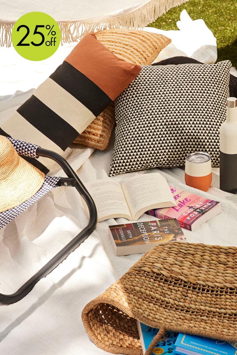 A collection of outdoor pillows and a straw tote.