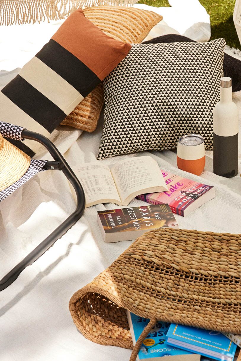 A collection of outdoor pillows and a straw tote.